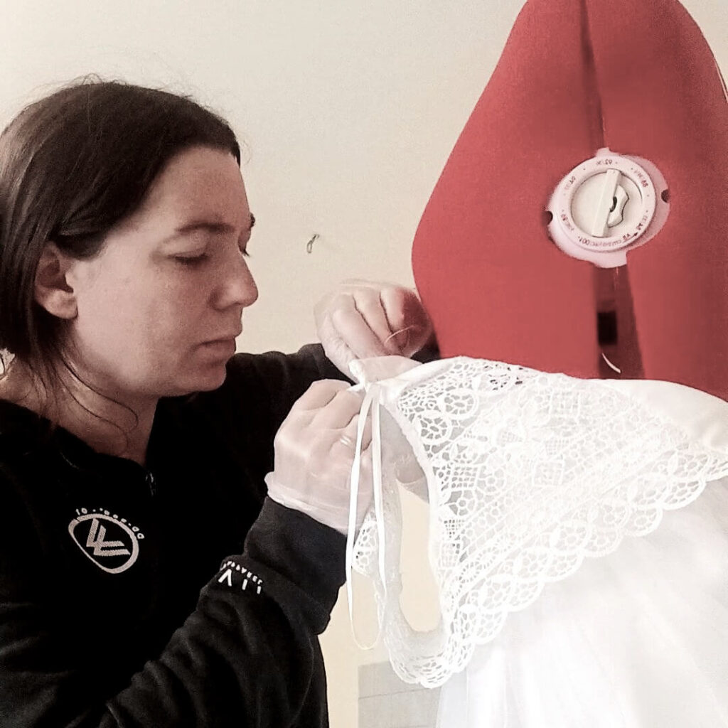 Une aiguille à la main Stéphanie Cousinard, couturière professionnelle, retouche une robe de mariée